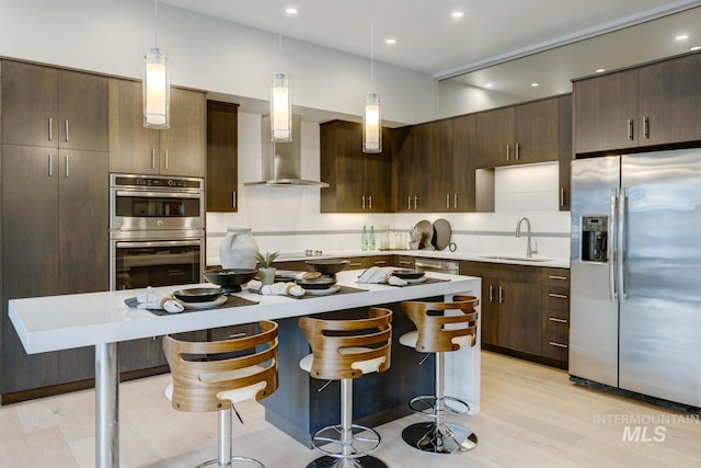 kitchen with dark brown cabinetry, sink, a center island, pendant lighting, and stainless steel appliances