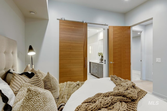 bedroom featuring connected bathroom and a barn door