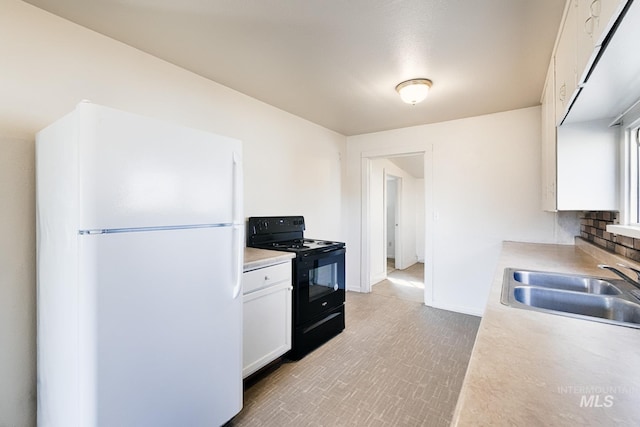 kitchen with a sink, black range with electric stovetop, light countertops, and freestanding refrigerator