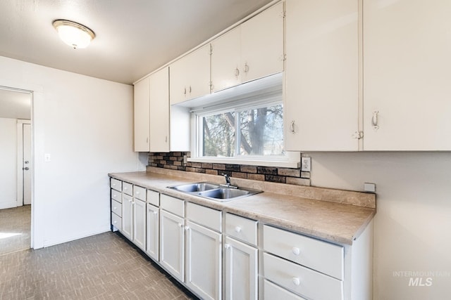 kitchen featuring white cabinetry, light countertops, tasteful backsplash, and a sink