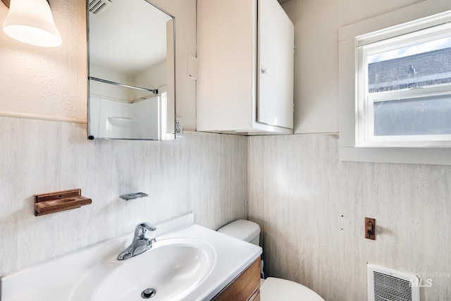 full bath with vanity, heating unit, visible vents, tile walls, and toilet