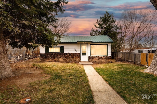 view of front facade featuring metal roof, a yard, and fence