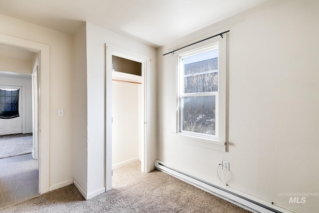 unfurnished bedroom featuring a closet, baseboards, baseboard heating, and carpet