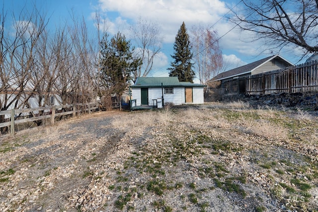 back of house featuring fence and metal roof