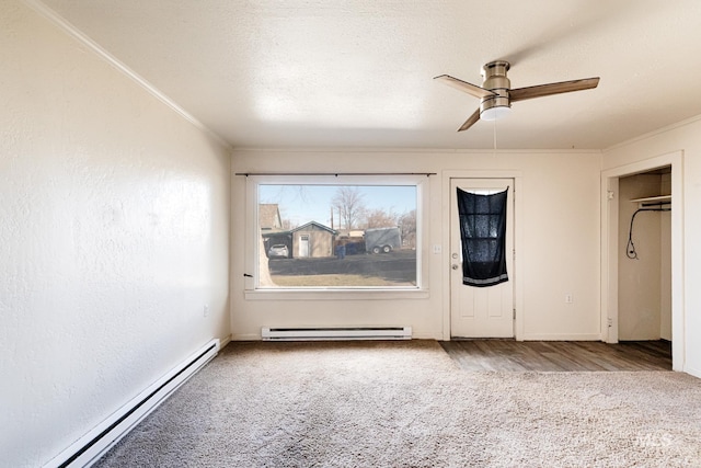 carpeted empty room featuring a baseboard heating unit, a textured ceiling, ornamental molding, and a ceiling fan