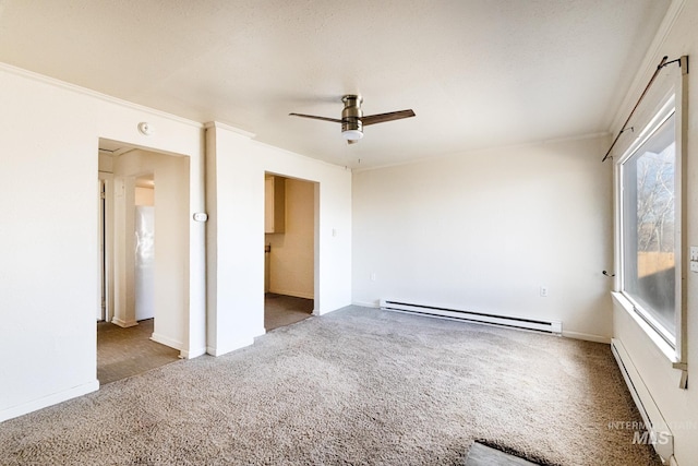 carpeted empty room featuring crown molding, baseboards, baseboard heating, and ceiling fan