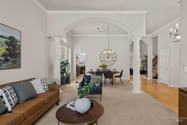 carpeted living room with an inviting chandelier, crown molding, and ornate columns