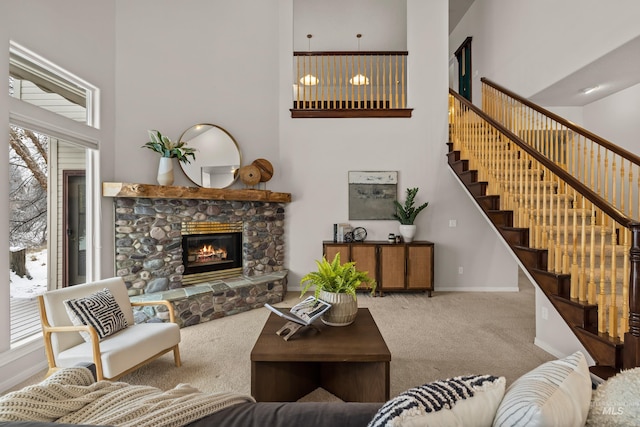 living room featuring a towering ceiling, a fireplace, and carpet floors