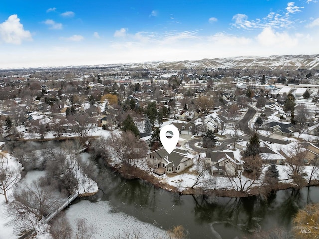 snowy aerial view featuring a water and mountain view