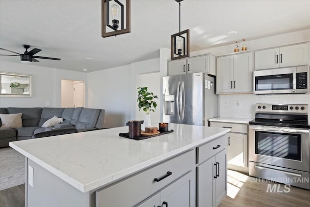 kitchen with dark wood finished floors, decorative backsplash, stainless steel appliances, and light stone counters