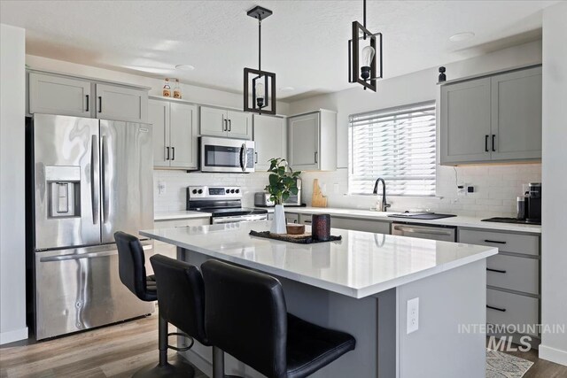 kitchen featuring a kitchen island, gray cabinetry, stainless steel appliances, and wood finished floors