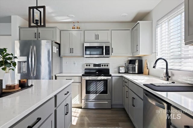 kitchen featuring backsplash, appliances with stainless steel finishes, dark wood-style flooring, and gray cabinetry