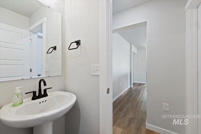 bathroom with a sink, baseboards, and wood finished floors