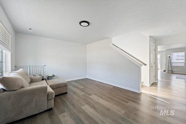 living room with stairway, baseboards, visible vents, and wood finished floors