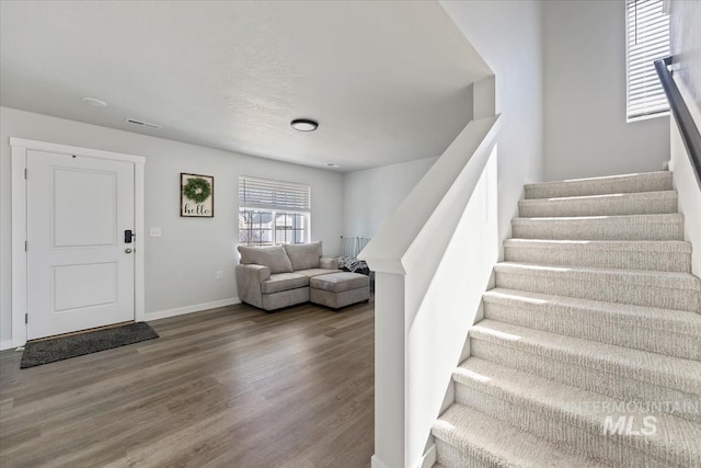 entryway with stairway, wood finished floors, and baseboards