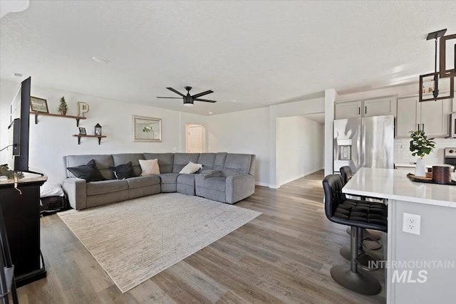 living area featuring baseboards, a ceiling fan, and wood finished floors