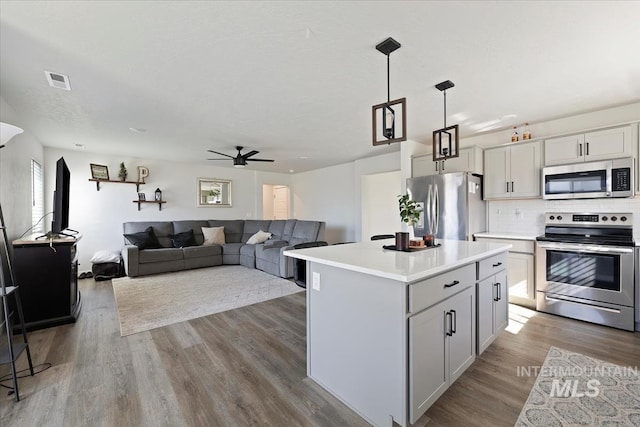 kitchen with visible vents, wood finished floors, appliances with stainless steel finishes, light countertops, and decorative backsplash