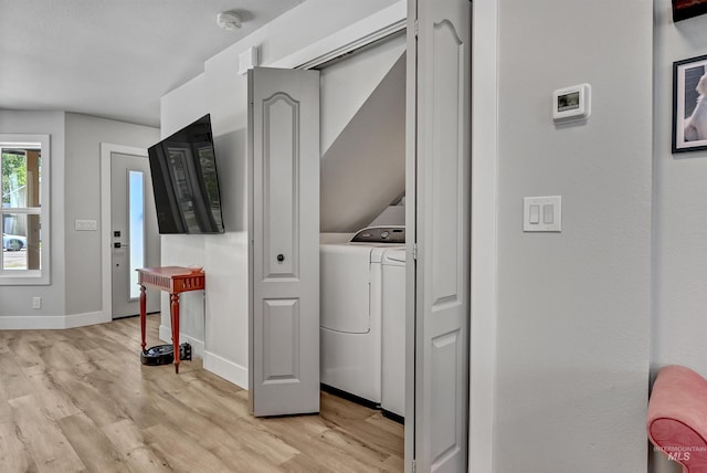 clothes washing area featuring washer / dryer, light wood-style flooring, and baseboards