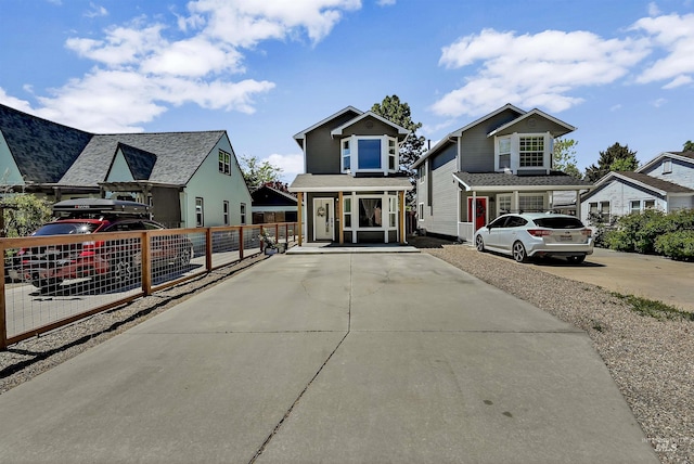 view of front of house featuring fence, concrete driveway, and a porch