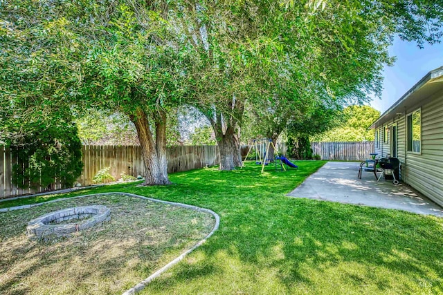 2209 S Plateau Dr, Nampa, ID 83686 - fenced backyard with a patio, a playground, and an outdoor fire pit