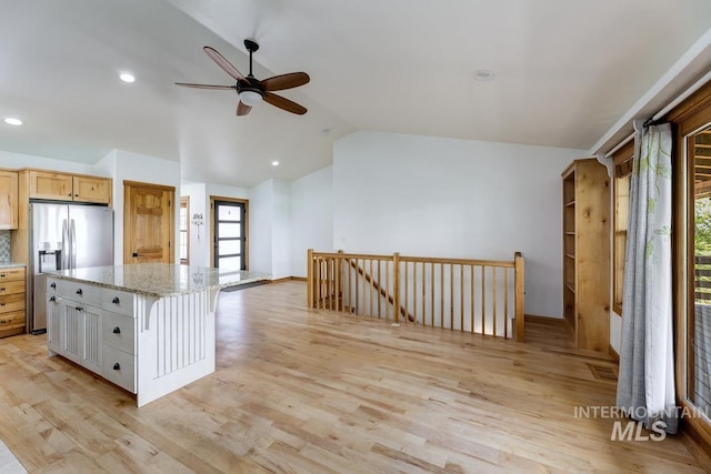 8315 Elk Ridge Ln, Middleton, ID 83644 - kitchen with lofted ceiling, stainless steel fridge, ceiling fan, light wood-type flooring, and light stone countertops