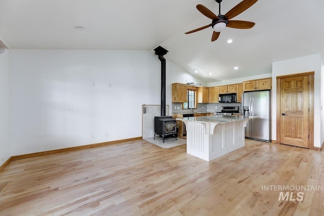 8315 Elk Ridge Ln, Middleton, ID 83644 - kitchen featuring appliances with stainless steel finishes, a wood stove, a ceiling fan, lofted ceiling, and backsplash
