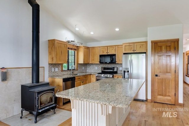 8315 Elk Ridge Ln, Middleton, ID 83644 - kitchen with appliances with stainless steel finishes, a wood stove, a kitchen island, light stone countertops, and vaulted ceiling