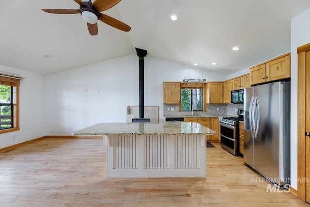 8315 Elk Ridge Ln, Middleton, ID 83644 - kitchen with appliances with stainless steel finishes, a wood stove, a kitchen island, vaulted ceiling, and a sink