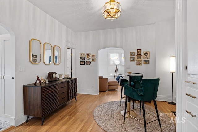 office area featuring arched walkways, a textured ceiling, and light wood-type flooring