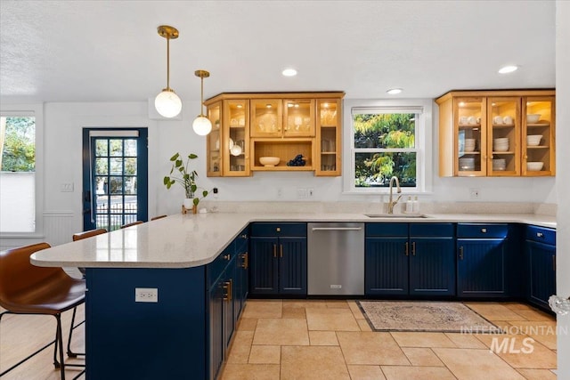 kitchen featuring blue cabinetry, a breakfast bar, stainless steel dishwasher, a sink, and a peninsula