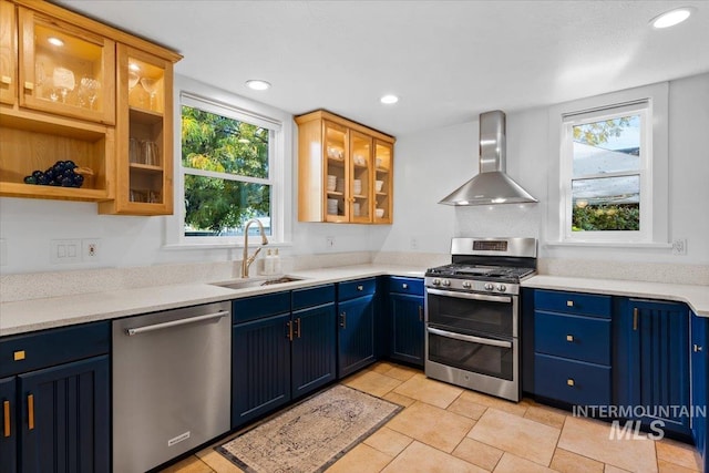 kitchen with recessed lighting, stainless steel appliances, blue cabinets, a sink, and wall chimney exhaust hood