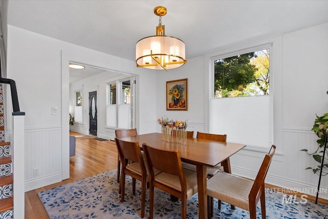 dining room featuring an inviting chandelier, light wood-type flooring, and wainscoting