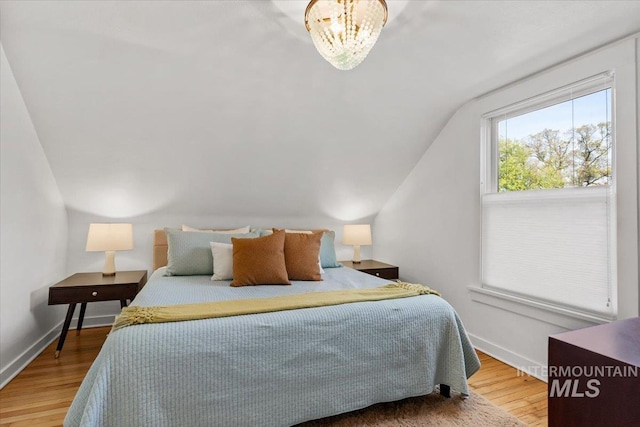 bedroom featuring baseboards, wood finished floors, and vaulted ceiling
