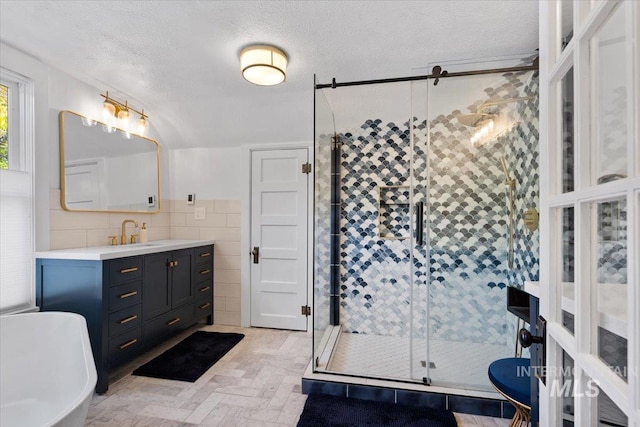 bathroom with vanity, tile walls, a textured ceiling, a soaking tub, and a stall shower