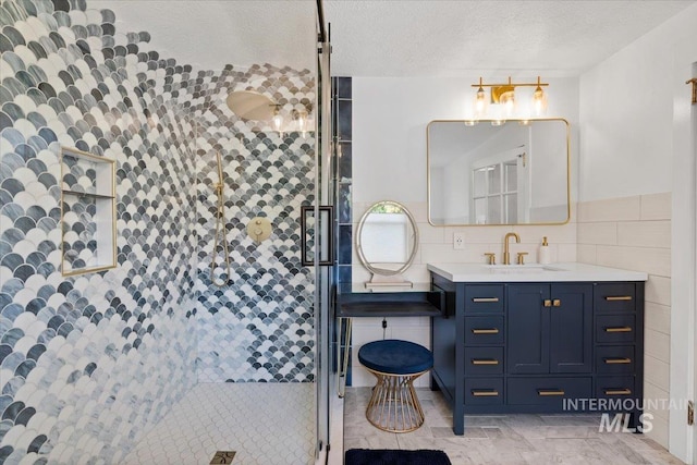 full bathroom featuring a tile shower, vanity, tile walls, and a textured ceiling