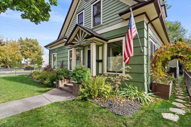 view of exterior entry featuring central air condition unit, fence, and a lawn