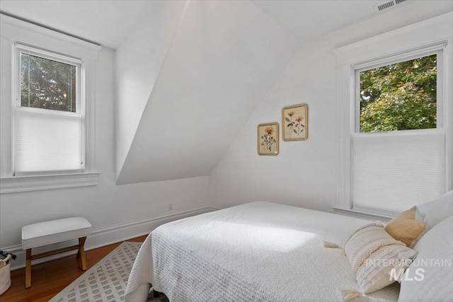 bedroom featuring multiple windows, vaulted ceiling, and wood finished floors