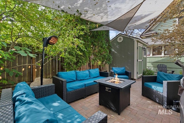 view of patio / terrace with an outdoor structure, an outdoor living space with a fire pit, fence, and a storage shed