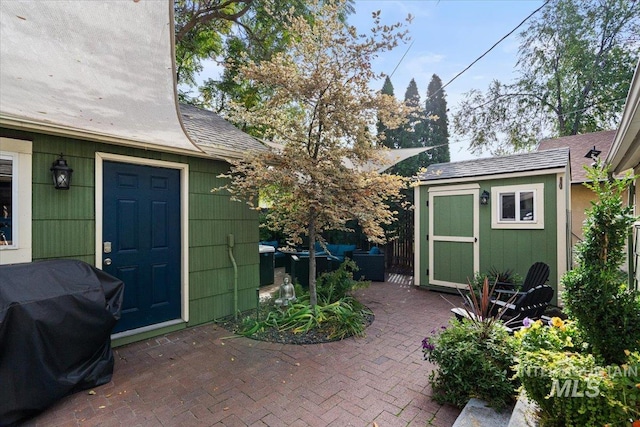 view of patio with an outdoor structure, grilling area, and a storage unit