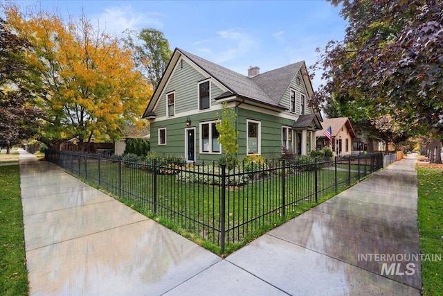 view of front of property featuring a chimney, a front yard, and a fenced front yard