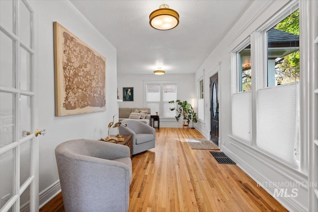living area with baseboards, visible vents, and light wood-type flooring