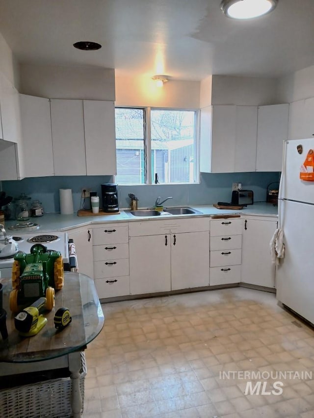 606 24th St, Lewiston, ID 83501 - kitchen with freestanding refrigerator, a sink, light countertops, white cabinets, and light floors