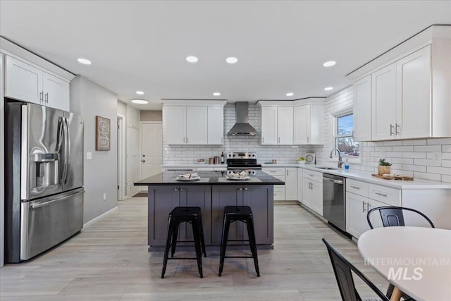 kitchen featuring white cabinets, wall chimney exhaust hood, a center island, and stainless steel appliances