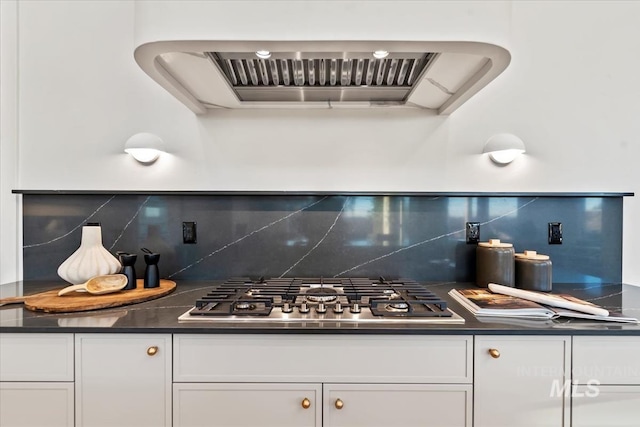 kitchen with stainless steel gas cooktop, premium range hood, dark countertops, and white cabinets