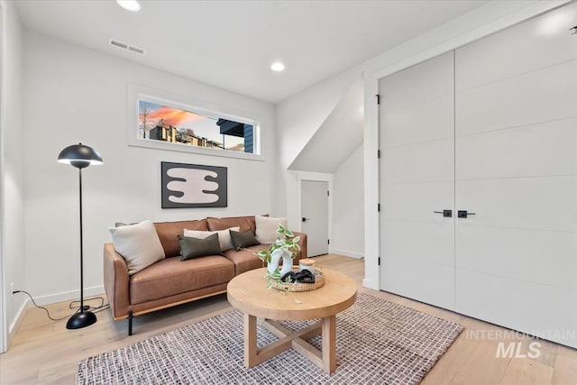 living room featuring light wood-type flooring, visible vents, baseboards, and recessed lighting