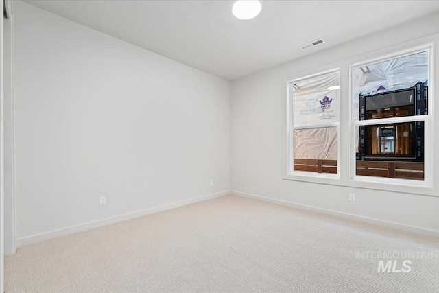 spare room featuring baseboards, visible vents, and carpet flooring