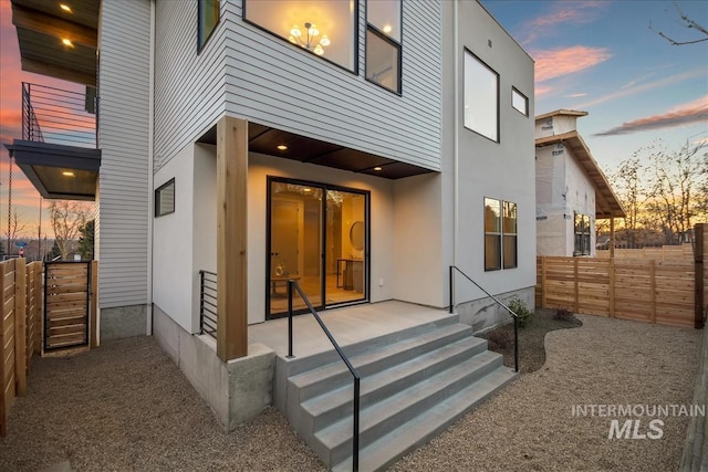 rear view of house featuring fence, a patio, and stucco siding