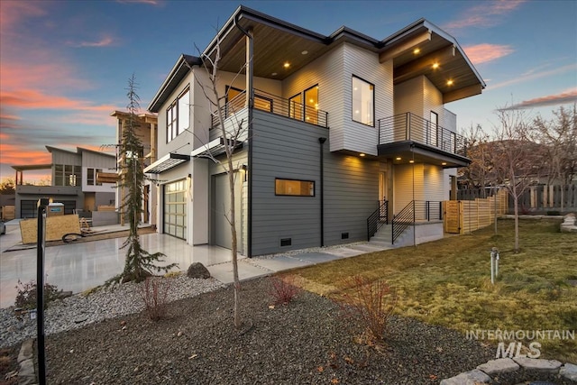 view of property exterior featuring a balcony, a garage, concrete driveway, a yard, and crawl space