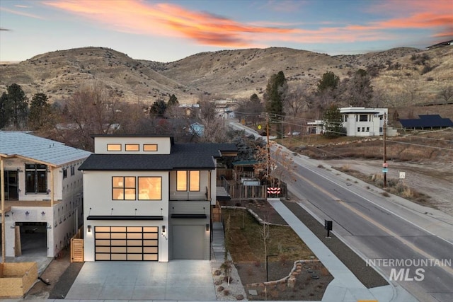 view of front of property featuring a garage, concrete driveway, a mountain view, and stucco siding