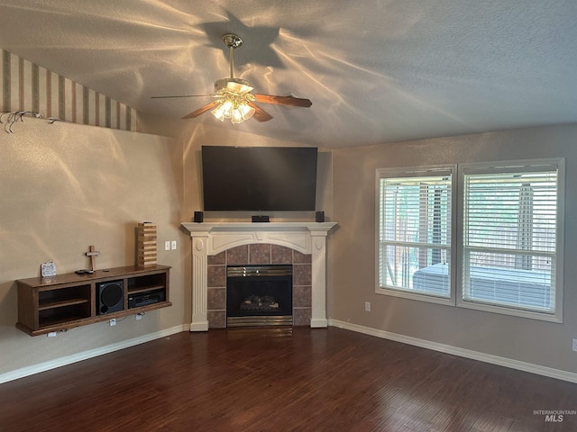 unfurnished living room with lofted ceiling, a textured ceiling, dark hardwood / wood-style flooring, ceiling fan, and a tiled fireplace